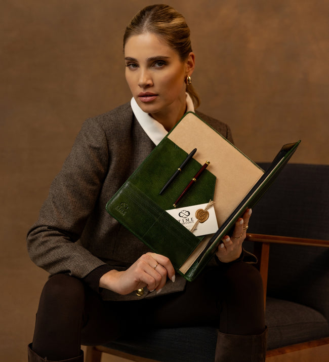 Woman displaying the open green Something Fresh portfolio with pens and a card inside
